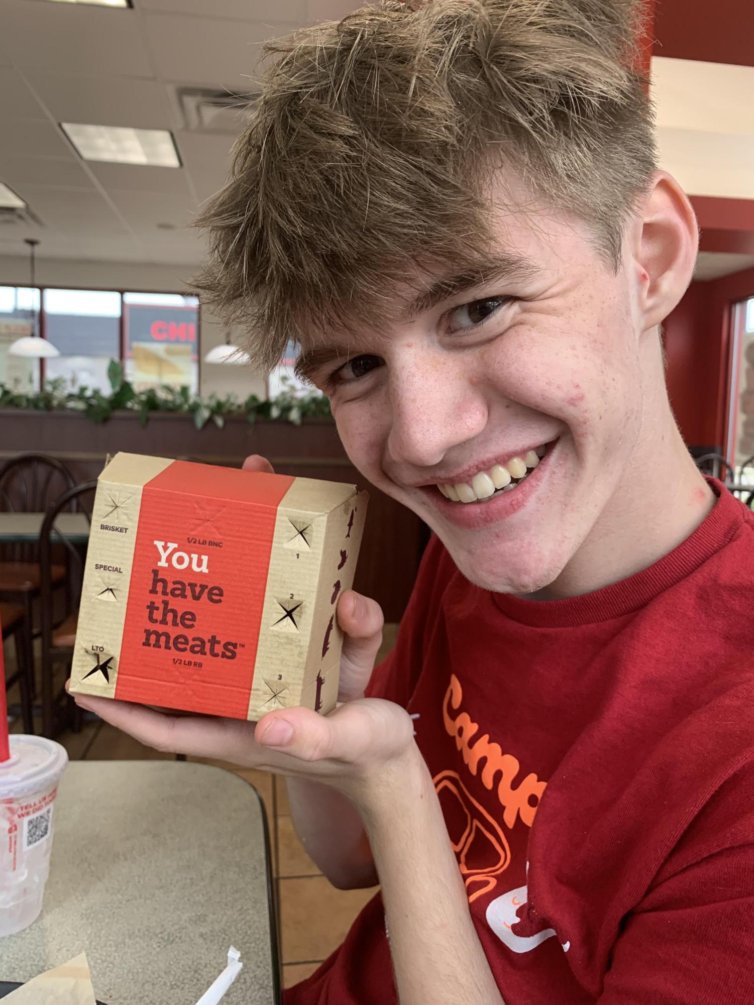 Washington student, Elijah Davis ('28), poses with a Steak Nugget Sandwich box.
